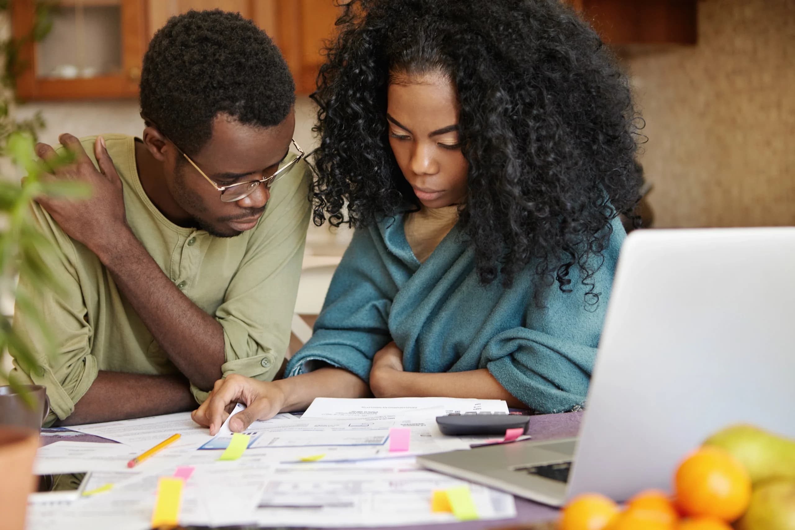 A couple is sitting together at their kitchen table reviewing their utility bills.