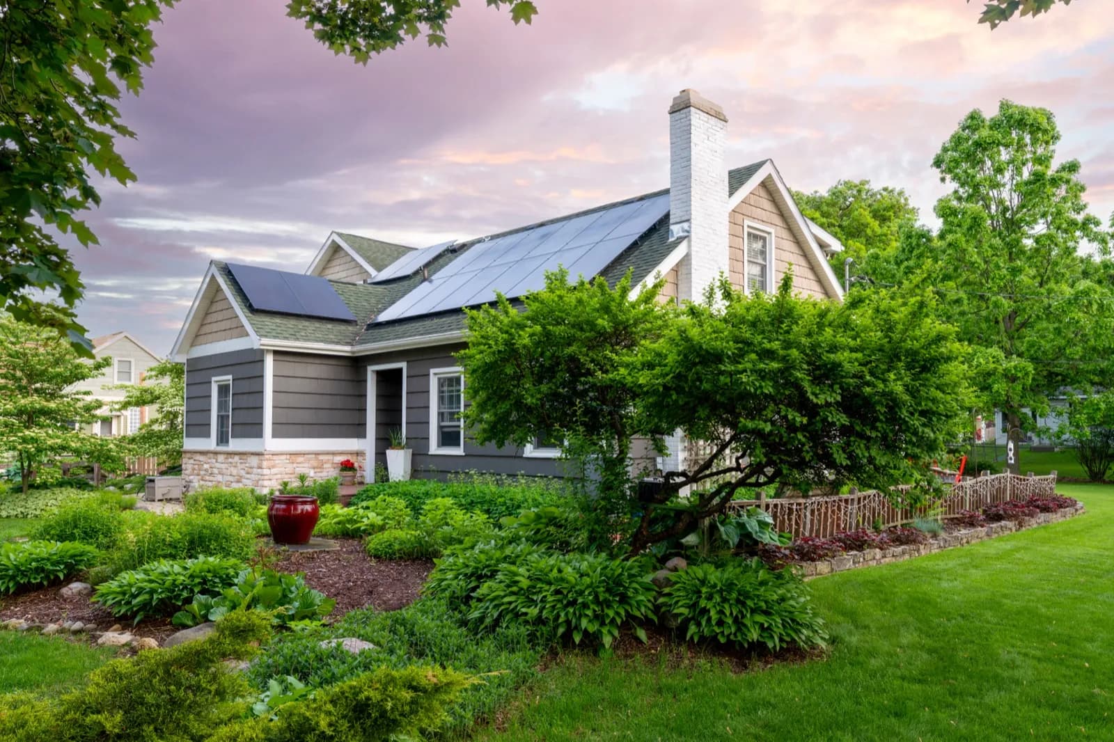 Home with rooftop solar panels surrounded by a lush garden